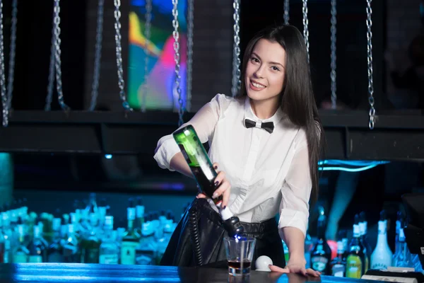 Smiling brunette bartender pouring martini — Stockfoto