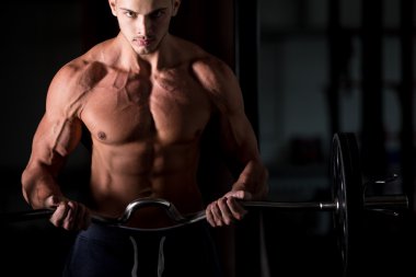 Young man lifting a barbell in fitness center 