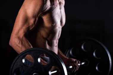 Muscular man lifting a barbell in fitness center