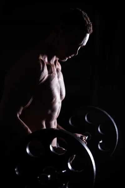 Muscular man doing weightlifting in fitness center — Stok fotoğraf