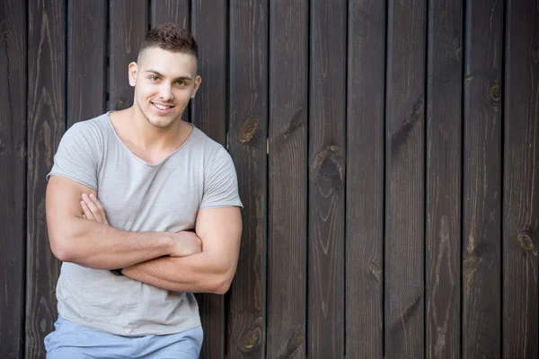 Ritratto di giovane uomo sorridente davanti al muro di legno — Foto Stock