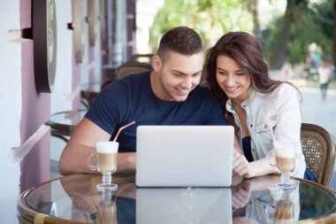 Happy couple with laptop at a cafe