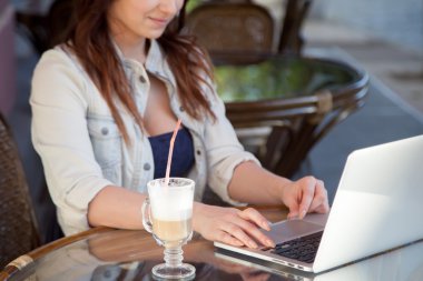 Young woman typing on laptop at a cafe