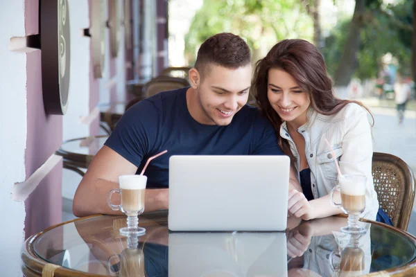 Happy couple with laptop at a cafe — Stockfoto