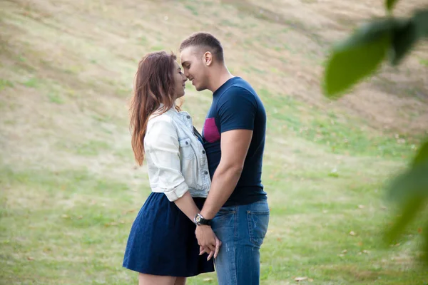 Young man and woman snuggling in park — Stockfoto