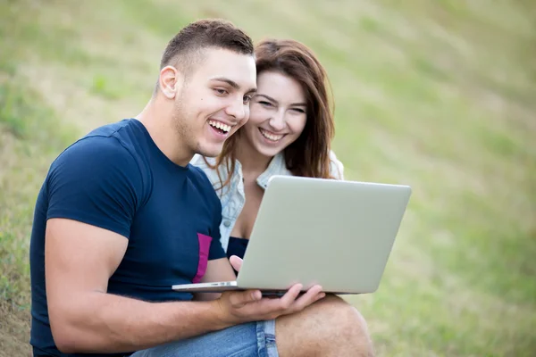 Couple using laptop on lawn — Stok fotoğraf