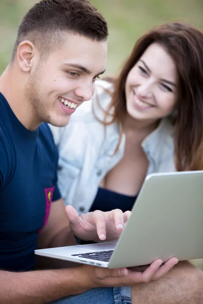 Couple sitting on lawn with laptop — Stok fotoğraf