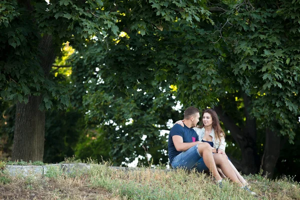 Casal apaixonado descansando sob as árvores — Fotografia de Stock
