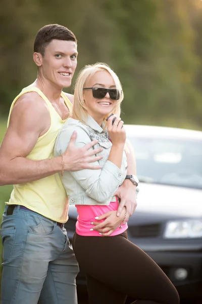 Couple embracing in front of car — Stock Photo, Image