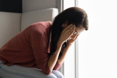 Frustrated stressed young Hispanic woman touching head with closed eyes, keeping stressed close posture, suffering from headache, hard migraine, healthcare problems with blood pressure