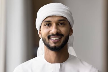 Head shot portrait social media profile picture happy handsome young Arabic man businessman student wearing traditional dress kandura white headscarf keffiyeh look at camera with smile make video call