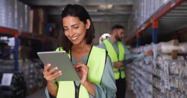 Woman wearing safety vest working in warehouse on tablet, inspecting or updating inventory data, involved in digital stocktaking, order processing, logistics coordination. Management and organization
