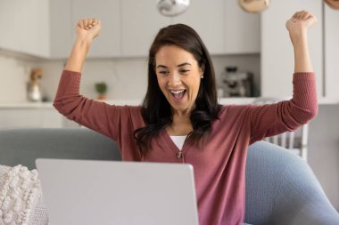 Joyful excited young Hispanic laptop user woman making yes gesture, shouting for joy at computer, winning prize, celebrating online triumph, Internet success, achievement, good, news