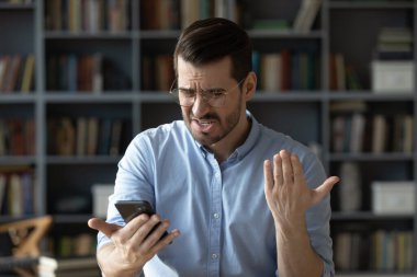 Bad news in message. Nervous angry young adult businessman remote working employee stressed reading rejection notice text negative customer feedback deal with critical app error on smartphone screen