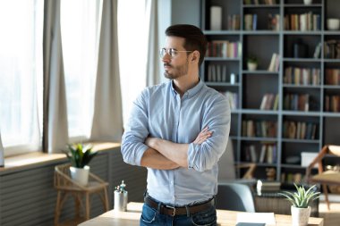 Future vision and forward thinking. Pensive young man business professional entrepreneur ceo stand in office workplace with arms crossed visualize big project success plan long term strategy set goals