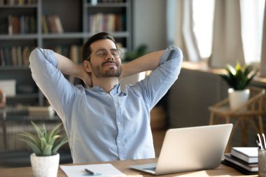 Workplace relaxation. Smiling satisfied young man business executive manager student lean back in comfy chair with closed eyes hands behind head take short break enjoy moment of peace feel stress free