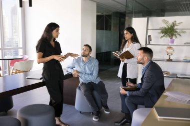 Takım geliştirme eğitimi. Genç bayan işletme koçu, modern ofis konuşmalarında çok ırklı iş adamlarından oluşan küçük bir grupta günlük atölye eğitimi veriyor.