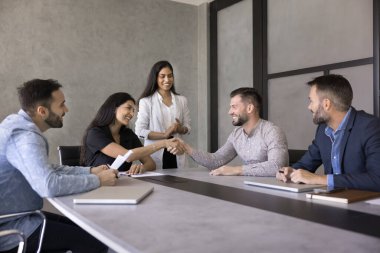Profesyonel işbirliği ve karşılıklı saygı. Genç ve mutlu iş adamı, konferans salonunda grup çalışması yapan kadın meslektaşının elini sıkıyor. Anlaşmaya varabilmemiz için yardımlarına minnettarız.