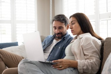 Dijital karar alma. Orta yaşlı aile çifti rahat koltukta rahatlamaya çalışır. İnternetteki ev geliştirme fikirleri için hafta sonu gezisi için otel biletlerini online olarak ayırtmaya çalışır.