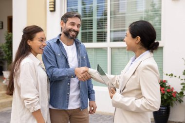 Mülk anlaşması yapmak. Milenyum çifti, elinde tablet olan emlakçıyla tokalaşıyor. Başarılı bir ev turu sonrası yeni ev kiralama anlaşmasını onaylıyor.
