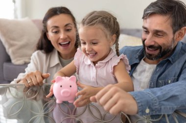 Mali sorumluluk üzerine ilk dersler. Gülümseyen üvey aile, komik domuz kumbarası oyunu oynayan evlatlık okul kızıyla konuşuyor. Çocuklara ekonomik tasarruf konusunda temel para becerilerini öğretiyor.