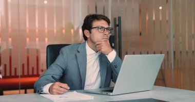 Latin işadamı, takım elbiseli analist, dizüstü bilgisayarla, araştırmalarla, geliştirmelerle, dosyalarla ve istatistiksel verilerle ilgili notlar yazıyor. Analiz, ofiste iş akışı