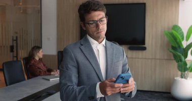 Genç Latin iş adamı, resmi takım elbiseli girişimci konferans odasında akıllı telefonu kullanıyor, e-postayla cevap veriyor, mesajlarda alınan bilgileri inceliyor, mobil uygulama üzerinden mesajlaşıyor. Teknoloji