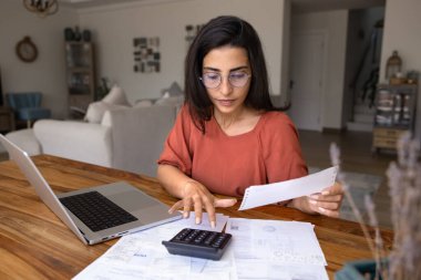 Evde çalışan genç Latin serbest muhasebeci, hesap makinesinde yazan, kağıt faturalarını kontrol eden, vergi ödemelerini yapan. Aylık giderleri sayan gözlüklü İspanyol kadın.