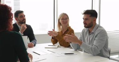 Proje üzerinde beyin fırtınası yapan dört müdürden oluşan çeşitli bir iş ekibi, işbirliği stratejisi, çalışma planı, yaratıcı pazarlama çözümleri, fikirler sunma, toplantı masasında konuşma