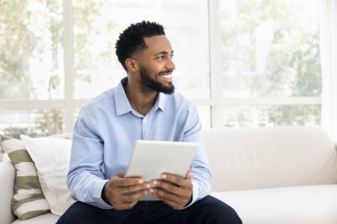 Afrikalı adam dijital tablet cihazıyla kanepede oturur, sosyal medya uygulaması ile sohbet eder, hobi edinir, eğlence ya da serbest iş için yapay zeka platformunu kullanır, hafta sonları evdeki kablosuz interneti kullanarak internetten eğlenir.