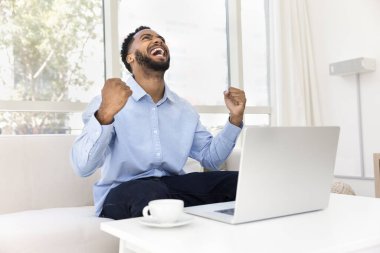 Mutlu Afrikalı adam inanılmaz, fantastik haberleri dizüstü bilgisayardan alır, evdeki kanepeye oturur yumruklarını sıkarak çığlıklar atar, evet hareketi yapar, başarının, başarının, zaferin tadını çıkarır.