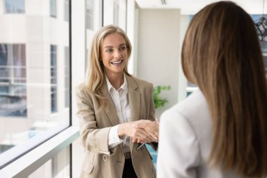 Mutlu, kendine güvenen genç iş kadını başarılı bir iş görüşmesinden sonra aday arıyor, partnerine el sıkışıyor, başarılı bir iş birliğine başlıyor, danışmanlık için teşekkür ediyor, gülümsüyor.