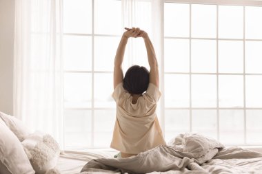 Yeni gün enerjisi. Huzurlu bir son sınıf öğrencisi olarak uyanıp, yatak odasındaki rahat otel odasına uzanıp, kollarını zevkle açarak, sabah ışığıyla büyük pencere duvarına yaslanarak uyanıyorum.