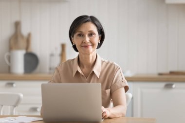 Ofis çalışanı. Gülümseyen bir portre kıdemli işkadını serbest çalışan bir girişimci. Uzaktan çalışan bir öğrenci. Mutfak masasında defter inceleme belgeleri üzerinde çalışıyor.
