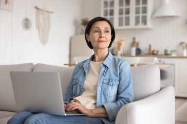 Dijital yazar. Portre, koltukta oturan ve rahat ev ofisinden not defteri üzerinde çalışan yaşlı bayan serbest yazardan esinlenmiştir. Yeni fikirleri yazmaktan dikkati dağılmış. Gelecek planlarının blog içeriği yarattığını hayal et.