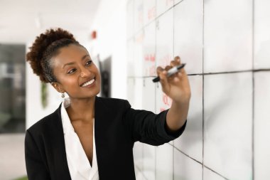 Genç, profesyonel bir zihniyet. Resmi takım elbiseli mutlu genç iş kadını portresi duvar şebekesi planlama çizelgesine işaretle yaratıcı bir hevesle görev çizelgesini düzenle ve sonuç görselleştirmesinin tadını çıkar