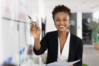 Gururlu bir kariyer başlangıcı. Portre mutlu genç iş kadını proje koordinatörü görsel çalışma kurulu yakınında poz veren pazarlama analisti işaret kağıdı tutucu kağıt raporları motivasyon enerjisiyle kameraya bakın