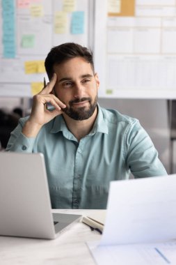 Yenilikçi bir düşünce. Düşünceli iş adamı veri analisti, kâğıtları incelemekten dikkati dağılan defterle ofis masasında oturuyor. Yeni bir plan fikri yaratıyor. Yaratıcı problem çözümü üzerinde kafa yoruyor, gülümsüyor.