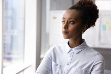 İş görüşü ve stratejik düşünce. Ciddi iş kadını portresi. Hırslı genç lider ofis penceresinin yanında duruyor. Mesafeye bakıyor. Boşluğu kopyala