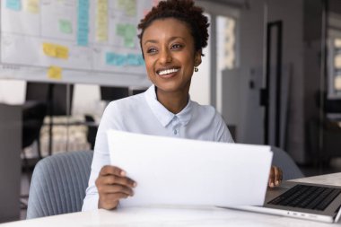 Bir fikrim var. Mutlu genç bayan girişimci veri analisti, elinde defterle masada oturup finansal belgeleri analiz ediyor. İlham verici bir gülümsemeyle, gelecekte yapılacak işler için yenilikçi bir iş stratejisi yaratıyor.