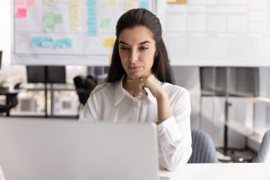 İşine odaklan. Çağdaş kadın pazarlama stratejisti ofis masasındaki not defteriyle dijital proje verilerini analiz ediyor başarılı iş akışı organizasyonu için beyin fırtınası yapan görevleri inceliyor.