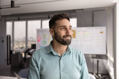 Yaratıcı vizyon. Modern ofiste kendinden emin genç işadamının durduğunu düşünen portre gülümseyerek kişisel gelişimi yansıtıyor gelecekteki başarı için stratejik yenilikleri görselleştiriyor.