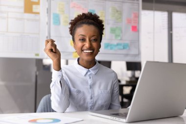 Evreka. Mutlu bir portre gülümseyen genç işkadını ofis çalışanı masa başında evrak işleriyle uğraşıyor kameraya bakıyor parmaklarını şıklatıyor problem çözümü bulmaya çalışıyor yenilikçi fikirler elde ediyor.