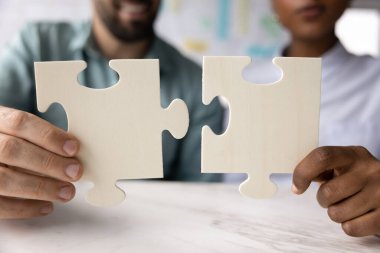 Başarılı takım çalışması için çeşitliliğe bağlanılıyor. İki farklı etnik çeşitlilikte genç iş adamının ellerini kapat. İş arkadaşları yapboz parçalarını birleştiriyor. İş ortaklığı ortaklığı birliği kavramı