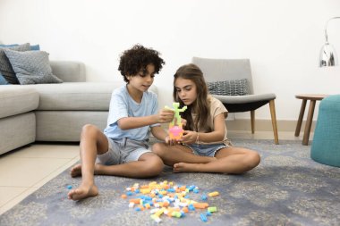 Modern oturma odasındaki halıya odaklanmış iki İtalyan çocuk renkli plastik bloklar inşa ediyorlar, konuşuyorlar, yaratıcı fikirleri paylaşıyorlar, hafta sonları evde yaratıcı takım çalışmasından keyif alıyorlar. Oyun zamanı