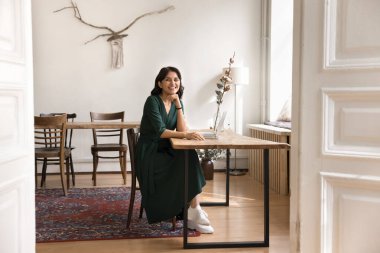 Genç iş adamı. Uzunluk portresi mutlu kadın bağımsız girişimci mesafe öğrenme öğrencisi çalışma masasında rahat bir şekilde oturmuş kameraya gülümseyerek bakıyor.