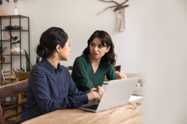 Yaratıcı ortaklık. İki genç çok ırklı iş kadını girişimci iş arkadaşları, defter tartışması stratejisi kullanarak proje üzerinde işbirliği yapıyor ve ofis masasında fikir alışverişinde bulunuyor. Boşluğu kopyala