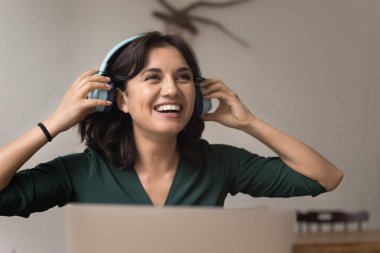 Uzaktan çalışma başarısı. Uzaktan çalışan mutlu gülen genç kadın konferans uygulamasındaki sanal konferansı tamamlayan video görüşmeleri sonrasında kulaklıklarını çıkarıyor.