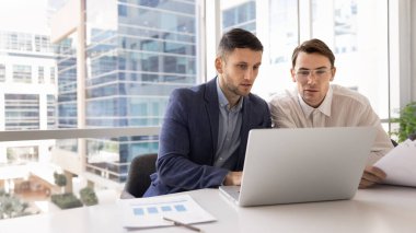 Kendine güvenen ürün yöneticisi iş arkadaşına danışıyor pazarlama raporunu gösteriyor, bilgisayardan iş arkadaşına sunuyor. Takım çalışması için bilgisayar kullanan iki profesyonel erkek. Sancak vuruşu