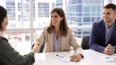 Mutlu iş kadınları buluşmada el sıkışıyor, başarılı bir ortaklık kuruyor, takım çalışması yapıyor, işbirliği yapıyor. İK 'dan profesyonel bir kadın adayla iş görüşmesinden sonra tokalaşıyor